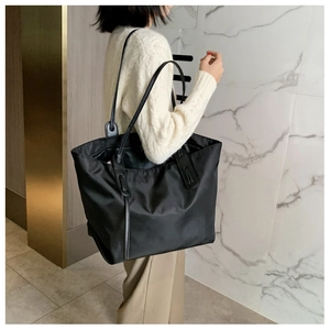 Side view of large black tote bag with long leather straps for daily commute use