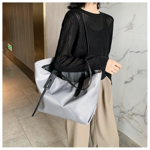 Close-up of gray nylon tote bag with black leather handles for commuting use
