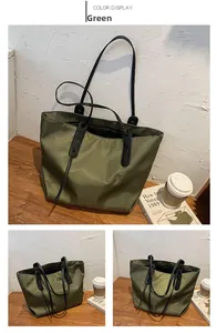 Detail view of large green nylon tote bag with black handles and reinforced stitching
