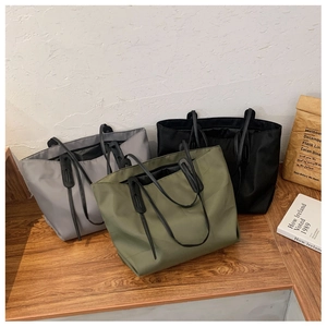 Three large tote bags in grey, army green, and black displayed on a wooden surface