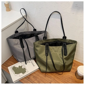 Detailed view of grey and olive green nylon tote bags on a wooden table setup
