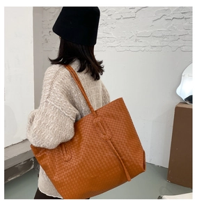 Close-up of orange-brown woven tote bag showing detailed matte PU leather texture