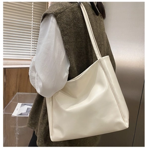 Side view of a large cream white tote bag worn by a model in a natural lifestyle setting