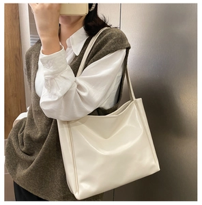 Close-up of minimalist cream tote bag showing smooth faux leather texture and shoulder straps