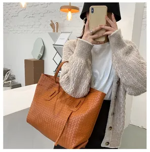 Close-up of orange-brown woven tote bag with Intrecciato leather pattern and top handles
