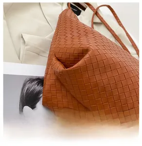 Detail view of woven leather tote bag bottom and intricate pattern in caramel brown