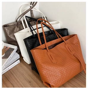 Detail shot of oversized woven tote bags in orange, black, white, and brown colors