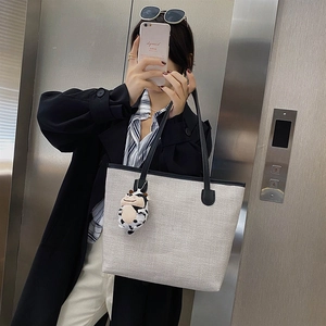 Large grey canvas tote bag with black leather straps and a cute cow plush pendant