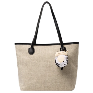 Minimalist beige canvas tote bag with black leather straps and a cute cow plush pendant