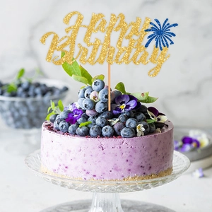 Golden Happy Birthday cake topper with blue fireworks on a blueberry mousse cake