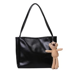 Minimalist black PU leather tote bag with cute plush bear pendant on a white background