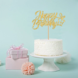 Detail of glitter gold Happy Birthday cake topper with gift box on a white cake
