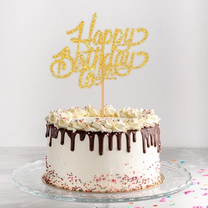 Glittery gold Happy Birthday to you cake topper on a chocolate cream birthday cake