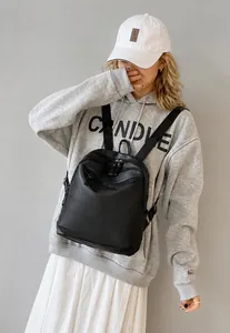 Détail d'un sac à dos en nylon noir avec poignée supérieure et fermetures éclair à plusieurs couches