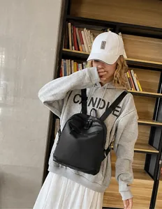 Mannequin portant un sac à dos en nylon noir minimaliste avec poche zippée dans une librairie