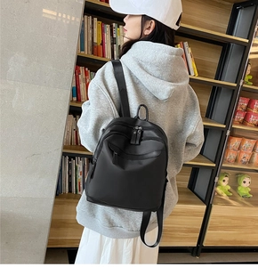 Sac à dos noir en nylon pour femme porté par un mannequin dans un décor de vie