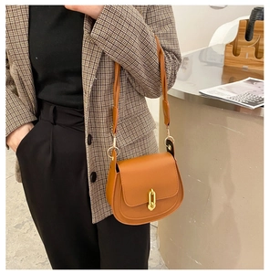 Dettaglio della borsa a sella marrone con elegante chiusura rettangolare in oro