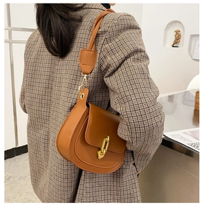 Dettaglio di una borsa a sella in pelle marrone con fibbia in metallo dorato a forma di U