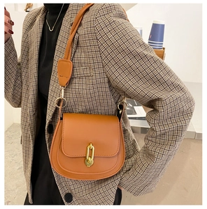 Dettaglio di una borsa a sella marrone vintage con catena dorata e tracolla regolabile
