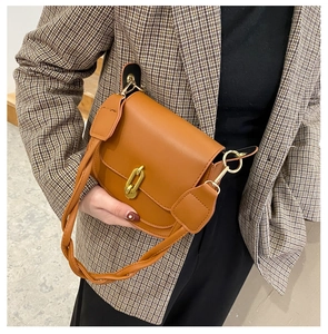 Dettaglio borsa a sella marrone vintage con fibbia a catena dorata e tracolla intrecciata