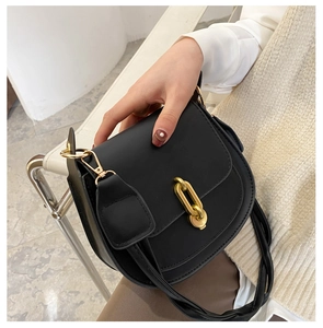 Dettaglio di una borsa a sella in pelle nera opaca con decorazione a catena dorata