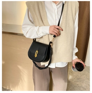 Dettaglio borsa a sella nera minimalista con fibbia dorata e tracolla in pelle
