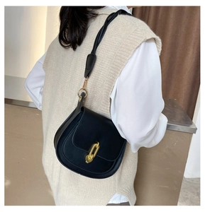 Dettaglio di una borsa a sella nera chic con fibbia a catena dorata e tracolla in pelle