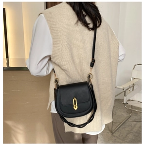 Dettaglio di una borsa a sella nera vintage con chiusura in metallo dorato sulla modella