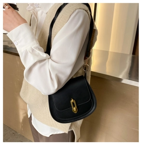 Dettaglio borsa a sella vintage in pelle nera con fibbia a catena metallica dorata