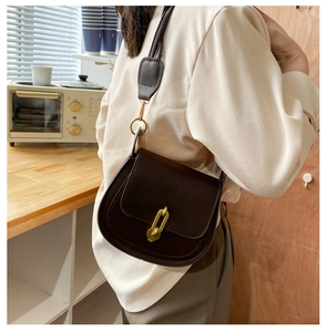 Dettaglio di una borsa a sella in pelle marrone scuro con chiusura dorata a forma di chiave
