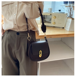 Dettaglio della borsa a sella vintage in pelle marrone scuro con catena dorata lucida