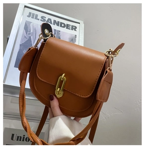Dettaglio di una borsa a sella marrone con finitura liscia e fibbia in metallo dorato