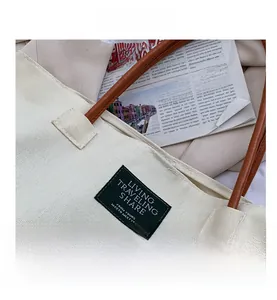 Dettaglio ravvicinato di una borsa tote in tela con manico in pelle marrone ed etichetta tessuta
