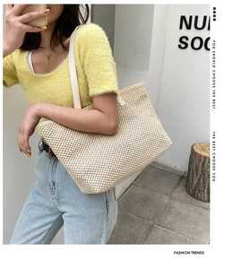 Close-up of woven tote bag texture with cream leather straps on a female model