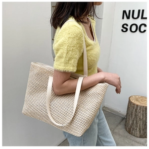 Detail of cross-weave straw pattern and cream leather straps on large tote bag