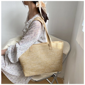 Detail of woven straw tote bag with smooth leather handles for a summer casual look