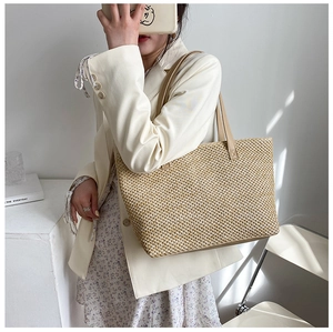 Macro detail of hand-woven straw tote bag with premium leather handles for women