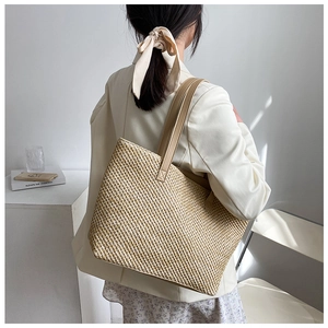 Detail showing the dense woven texture and leather straps of the large beige tote bag