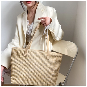 Detail shot of the woven texture and leather strap on this beige large capacity tote bag
