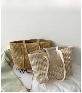 Detail of woven straw tote bags with leather handles in khaki and off-white colors