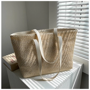 Detailed close-up of woven cream tote bag showing texture and leather handles in sunlight
