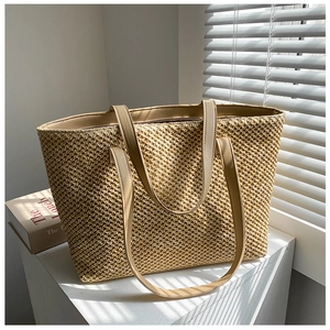 Detail of woven straw tote bag texture and faux leather handle in soft sunlight