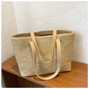 Macro shot of woven straw texture and light khaki synthetic leather handle on tote bag