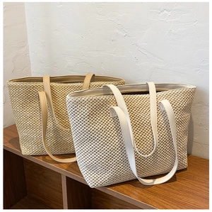 Close-up of woven straw tote bags in beige and khaki with leather handles
