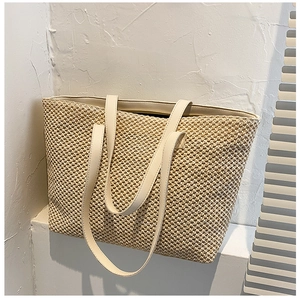 Macro detail of the woven straw texture and faux leather strap on this large tote bag