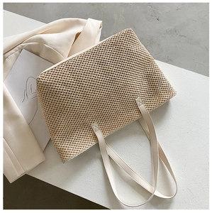 Detail of the woven texture and smooth synthetic leather handle on beige tote bag