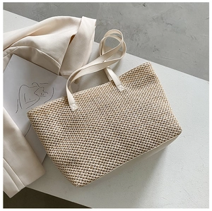 Detailed close-up of beige woven tote bag with leather handle on minimalist background