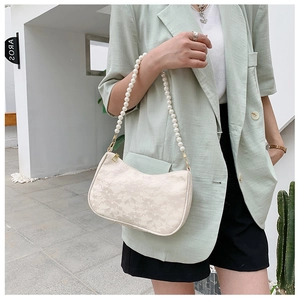 Detail shot of the cream lace fabric texture and elegant white pearl shoulder strap