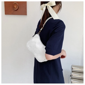 Detail of white lace texture and large faux pearl strap on a vintage underarm bag