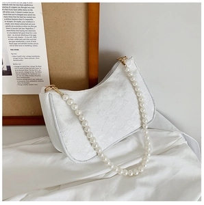 Detailed macro view of white lace underarm bag with floral texture and pearl chain handle